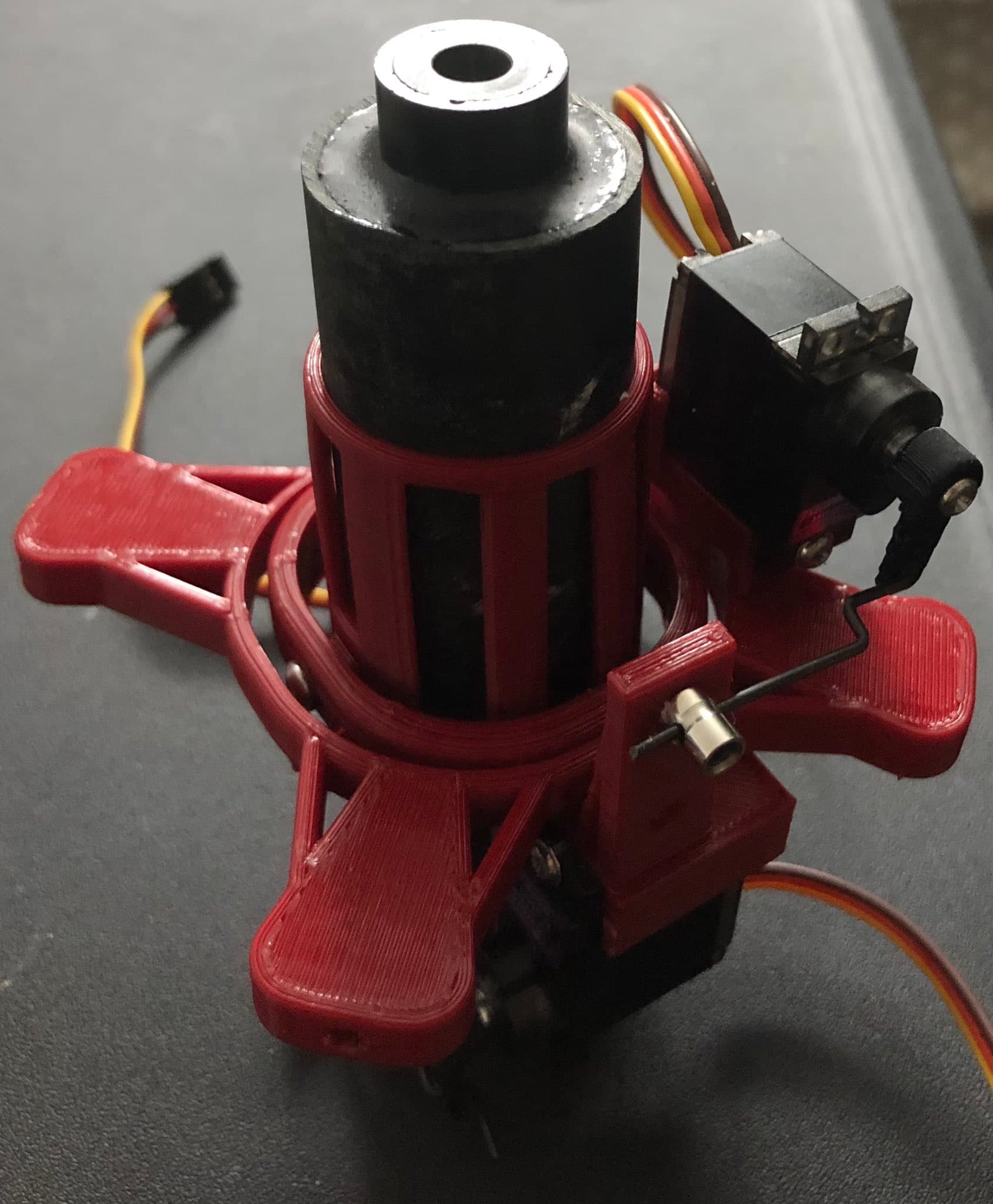 A 3D-printed thrust-vector mount cradling a motor, servos wired and ready.