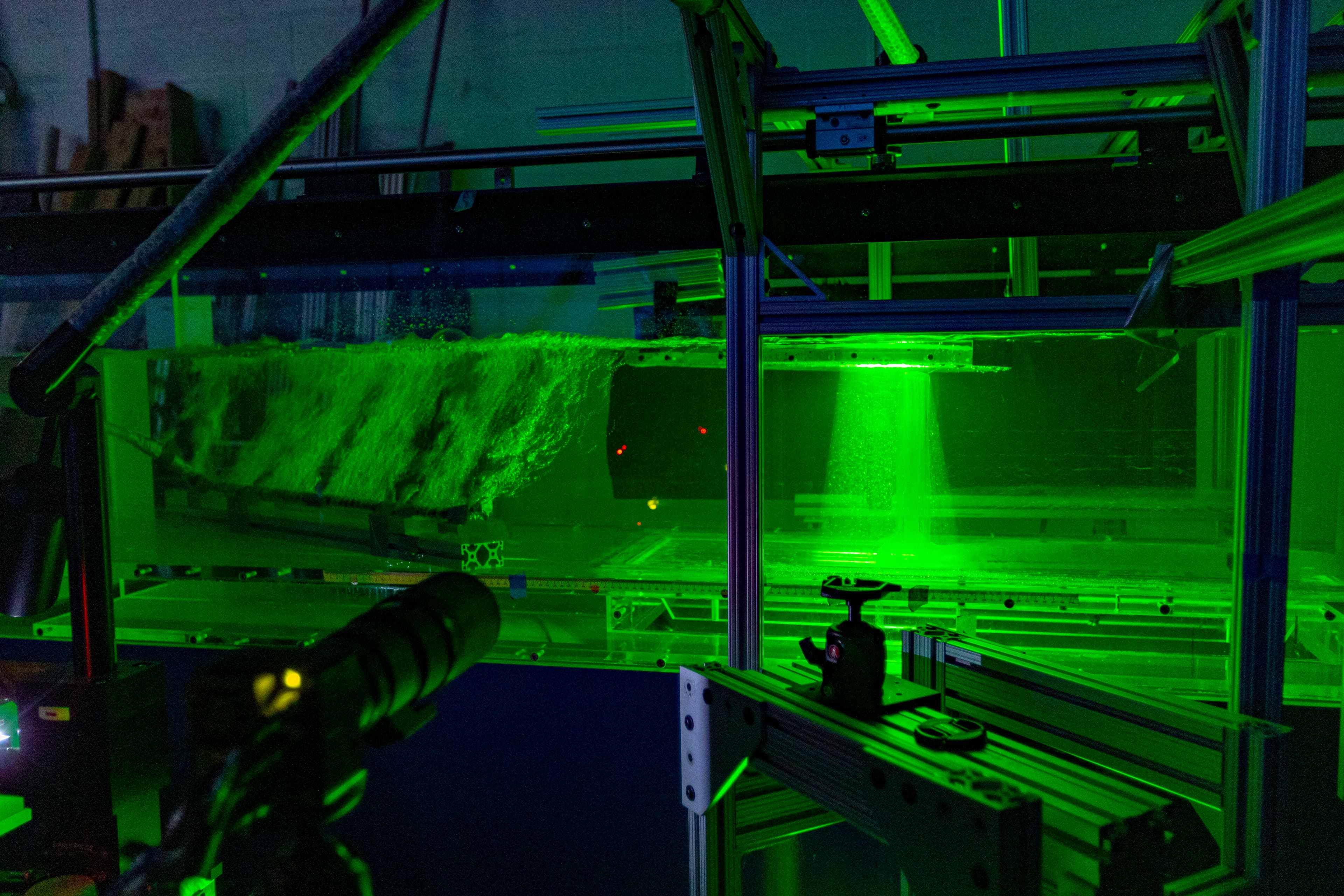 Particle image velocimetry in the flume: a green laser sheet cutting through seeded flow.