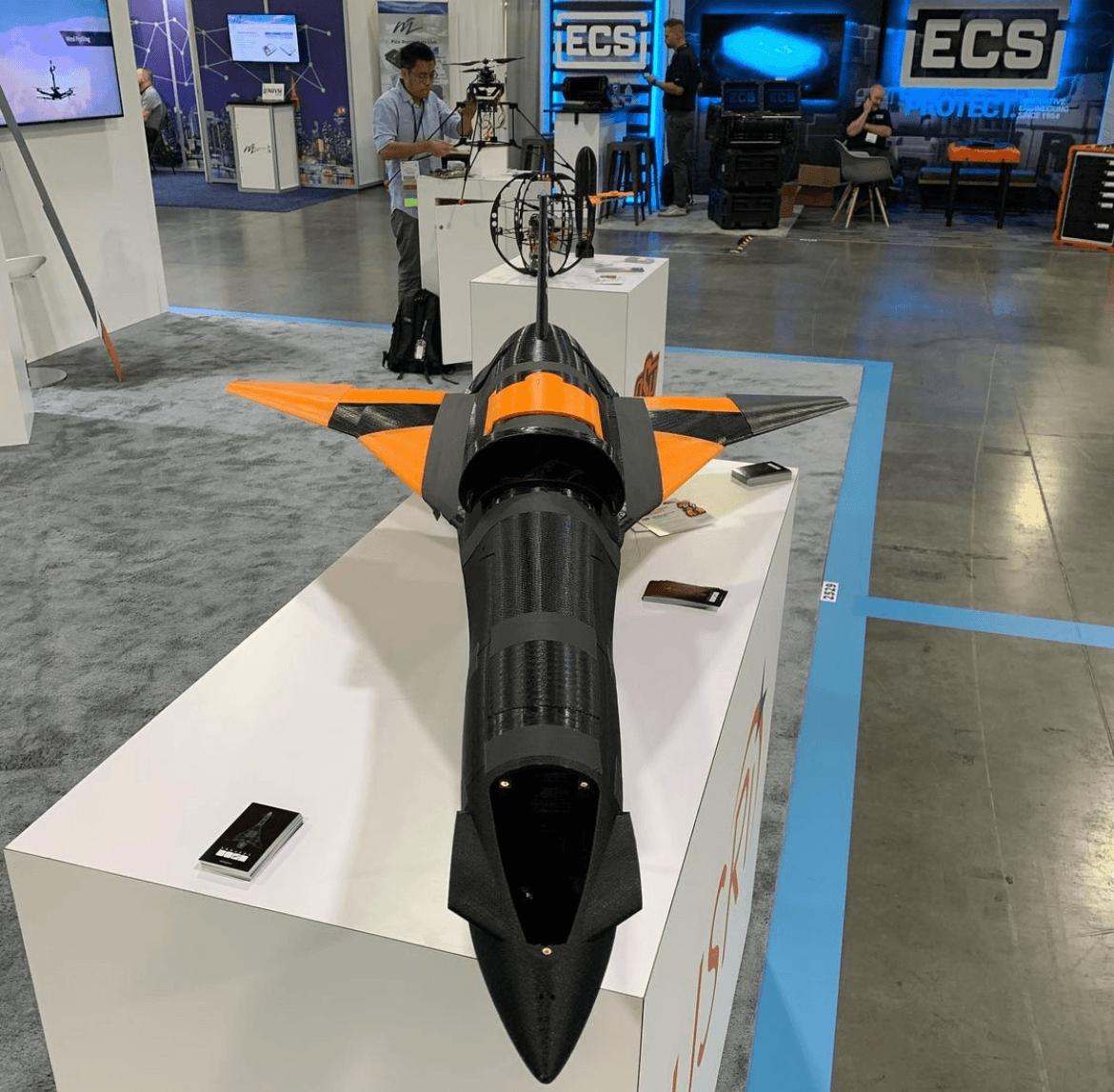 Black-and-orange Project Boom airframe on display at a conference booth.