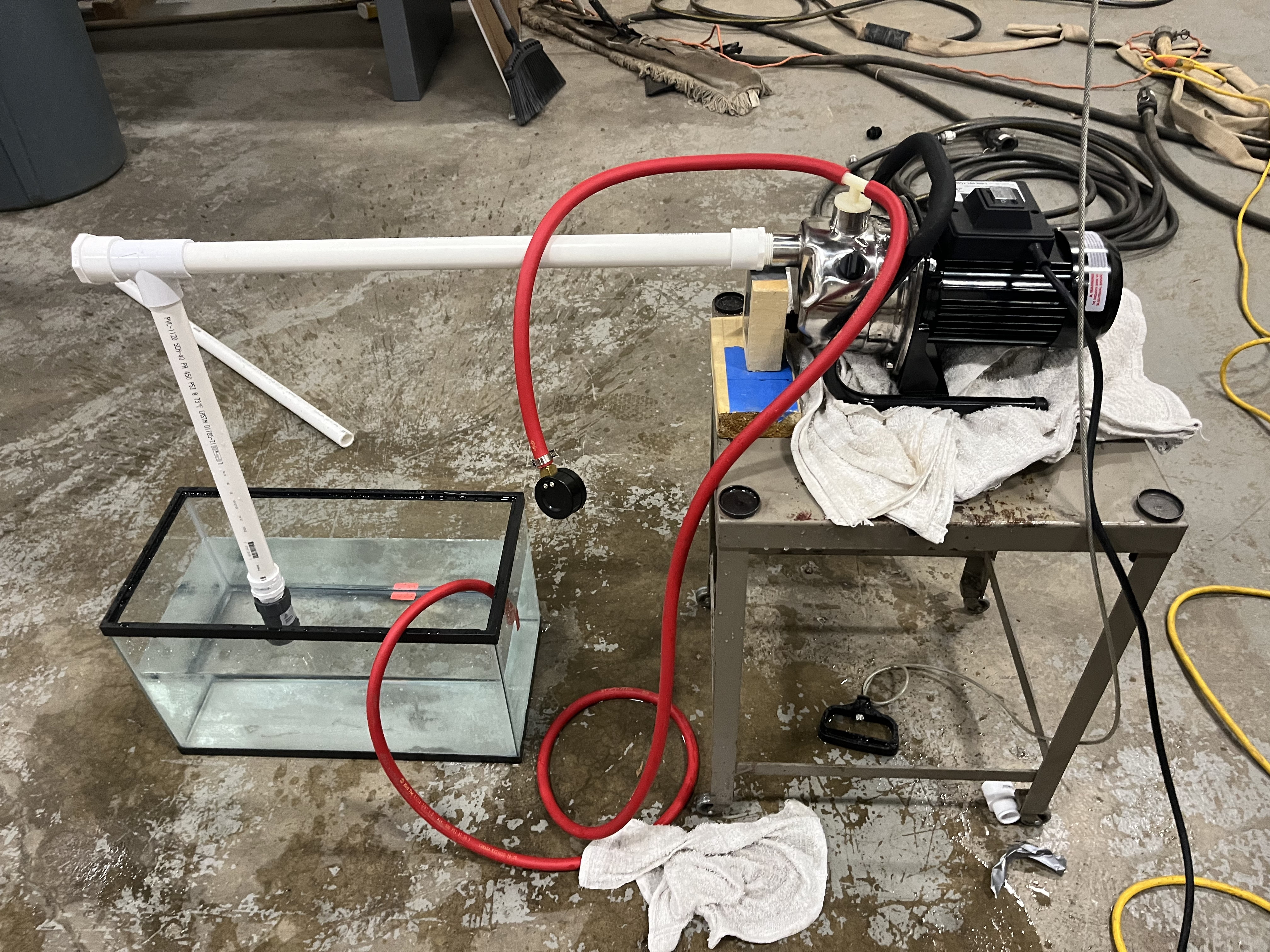 A shop-built nanobubble generator: pump, red hoses, PVC sparger, and a glass tank.